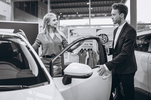 Mujer hablando con el vendedor en una sala de exposición de automóviles