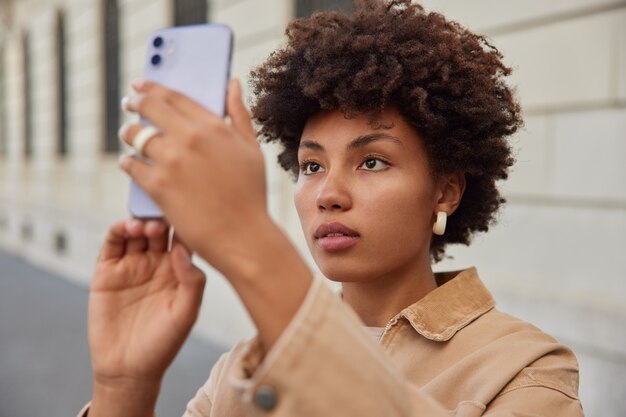 Mujer hace selfie en la cámara frontal del teléfono inteligente posa para tomar una foto de sí misma afuera mientras hace una excursión en la ciudad usa ropa elegante tiene tiempo libre