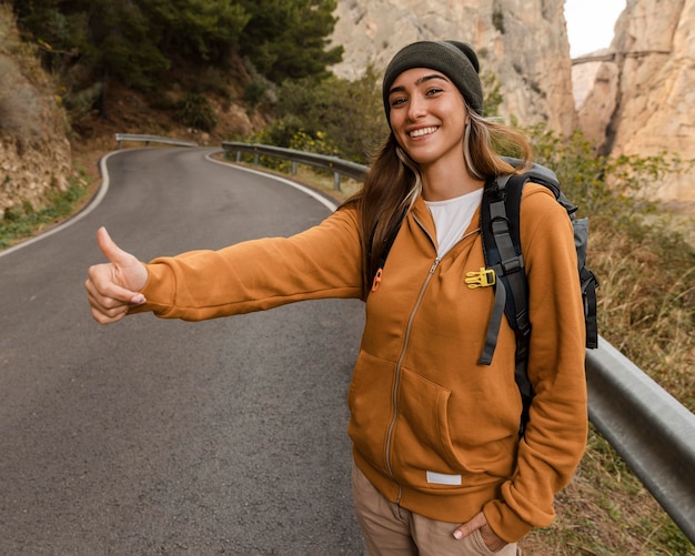 Mujer haciendo autostop para un coche en las montañas