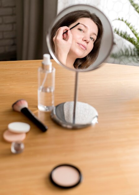 Mujer haciendo las cejas en el espejo