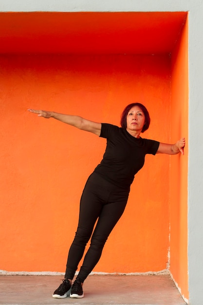 Mujer haciendo ejercicio físico mientras se apoya en una pared