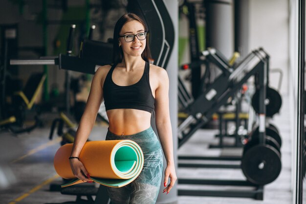 Mujer haciendo ejercicio en el gimnasio con colchoneta de yoga