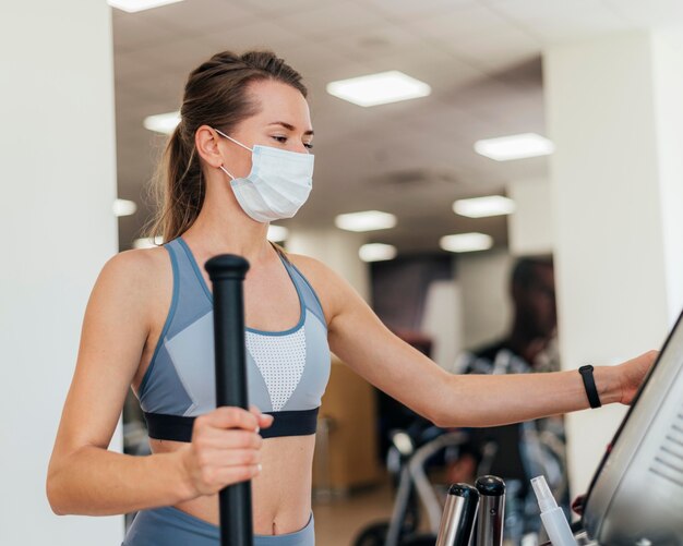 Mujer haciendo ejercicio en el gimnasio con máscara