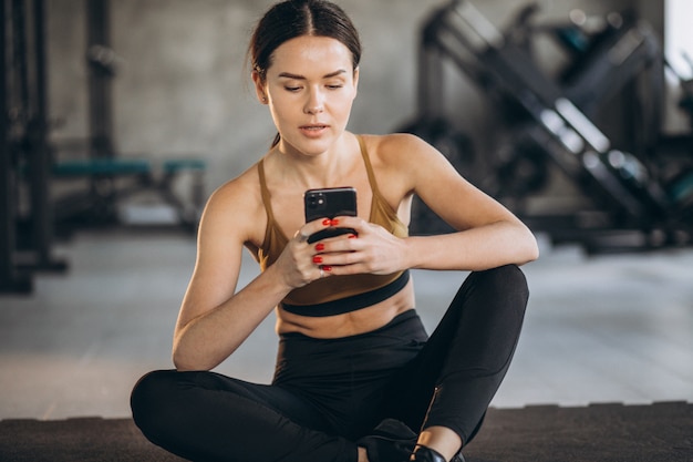 Mujer haciendo ejercicio a través del programa en línea en el gimnasio