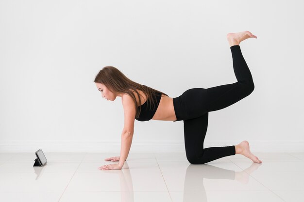 Mujer haciendo ejercicios de fitness desde teléfono móvil