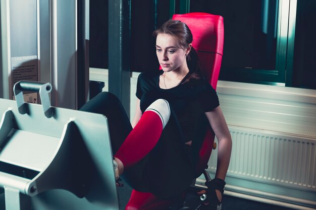 Mujer haciendo entrenamiento físico en una máquina de empuje de extensión de pierna