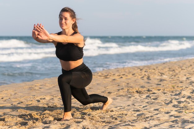 Foto gratuita mujer haciendo estocadas en la playa