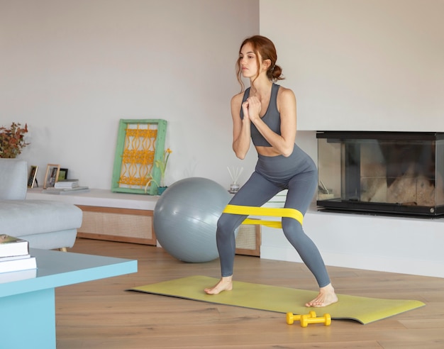 Mujer haciendo fitness en casa con banda