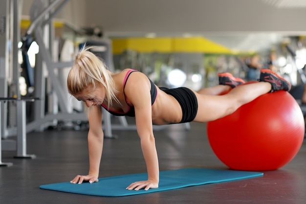 Mujer haciendo flexiones sobre una pelota roja