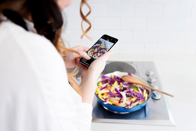 Mujer haciendo foto de comida en sartén