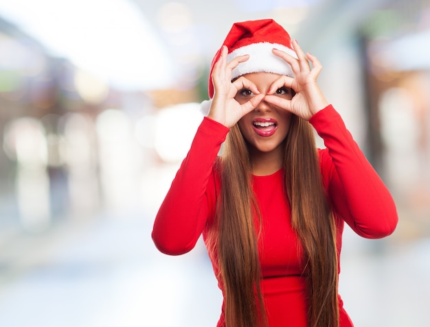 Mujer haciendo gafa de dedos en un centro comercial