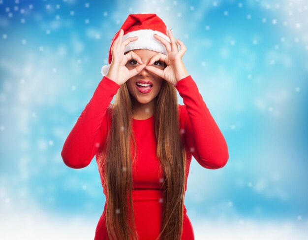 Mujer haciendo gafa de dedos mientras nieva