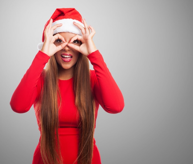 Mujer haciendo gafas de dedos en un fondo gris