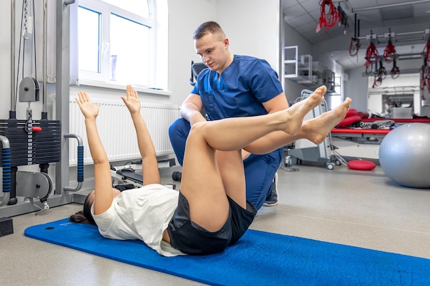 Foto gratuita mujer haciendo gimnasia con la ayuda de su joven fisioterapeuta