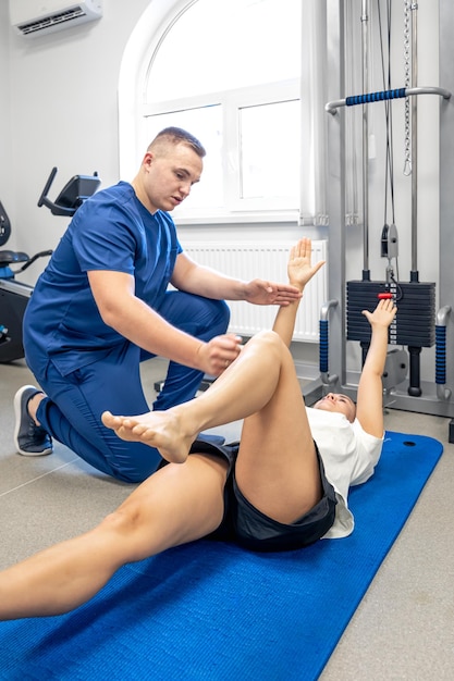 Foto gratuita mujer haciendo gimnasia con la ayuda de su joven fisioterapeuta