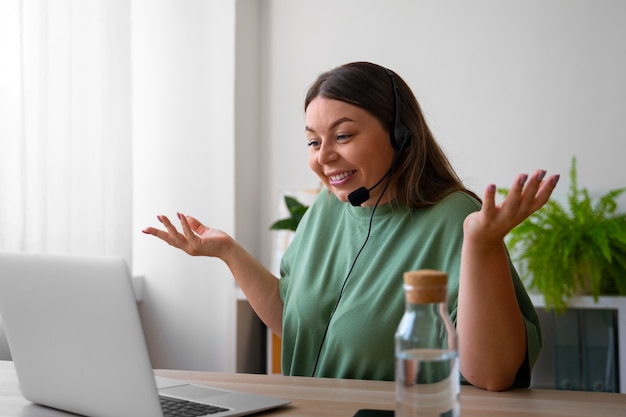 Foto gratuita mujer haciendo una llamada de video en casa en una computadora portátil con auriculares