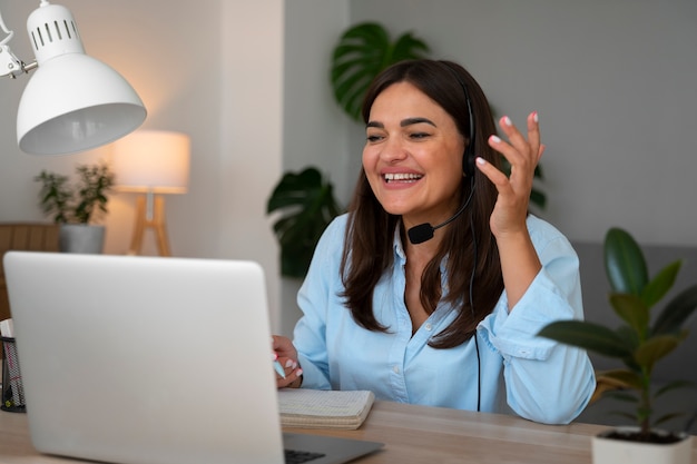 Mujer haciendo una llamada de video en casa en una computadora portátil con auriculares