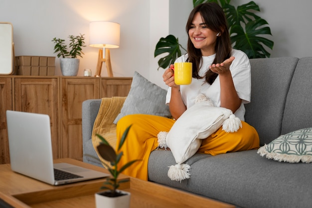 Foto gratuita mujer haciendo una llamada de video en casa en un dispositivo portátil