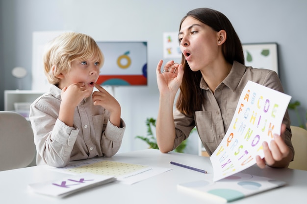 Foto gratuita mujer haciendo logopedia con un niño rubio