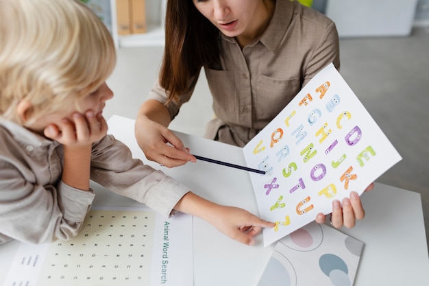 Mujer haciendo logopedia con un niño en su clínica