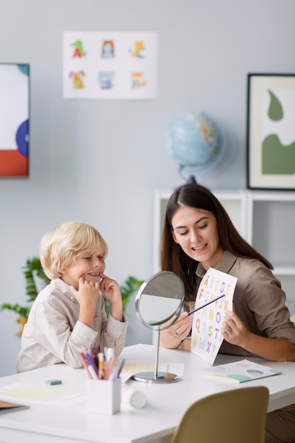 Mujer haciendo logopedia con un niño en su clínica