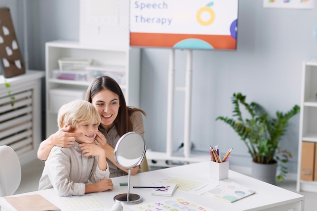 Mujer haciendo logopedia con un niño en su clínica