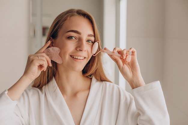 Mujer haciendo masaje con piedra gua sha y rodillo facial