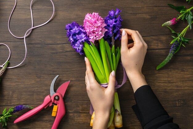 Mujer haciendo moda ramo moderno de diferentes flores sobre superficie de madera