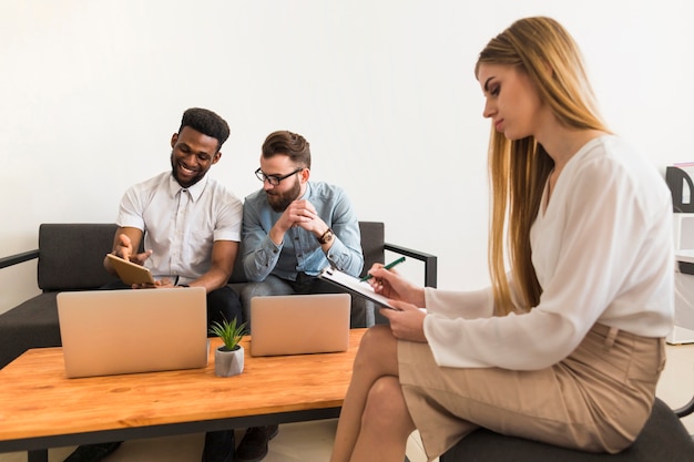 Foto gratuita mujer haciendo notas cerca de colegas que trabajan