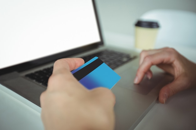 Mujer haciendo pagos en línea usando laptop y tarjeta de crédito
