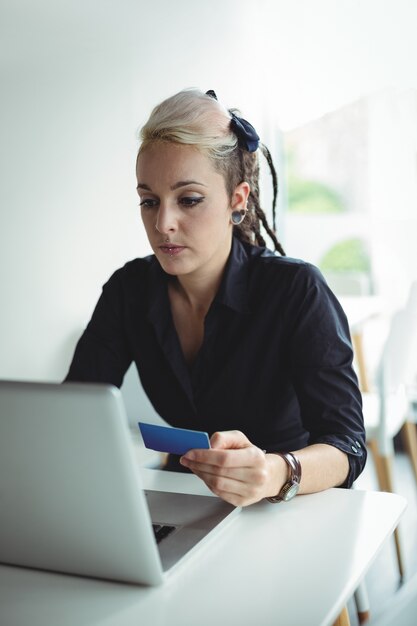 Mujer haciendo pagos en línea usando laptop y tarjeta de crédito