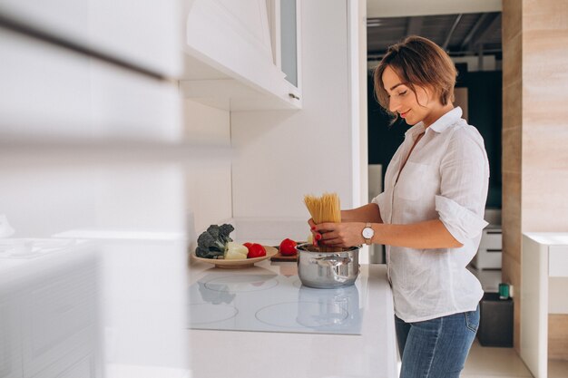 Mujer haciendo pasta para cenar en la cocina