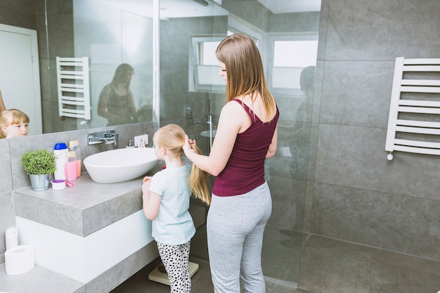 Mujer haciendo pelo de hija