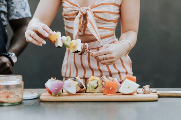 Mujer haciendo pinchos de barbacoa para una fiesta.