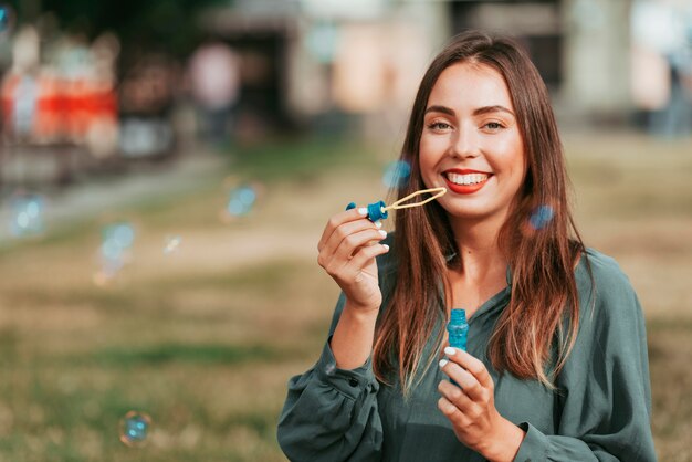 Mujer haciendo pompas de jabón con espacio de copia