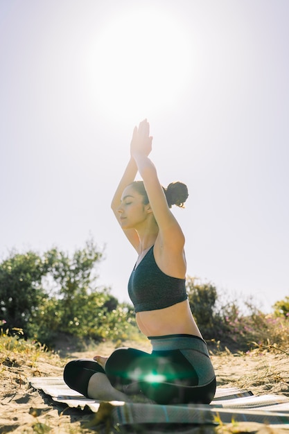Mujer haciendo pose de yoga en el sol