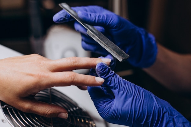 Mujer haciendo procedimiento de manicura en un salón.