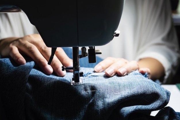 Mujer haciendo remiendo de jeans usando la máquina de coser - concepto de costura de bricolaje casero