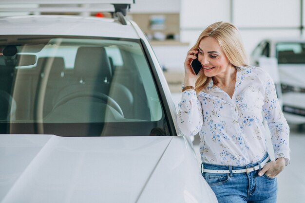 Mujer haciendo selfie en el auto en una sala de exposición de automóviles