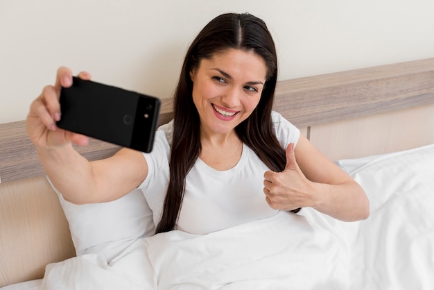 Mujer haciendo selfie en habitación de hotel