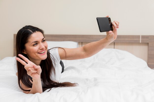 Mujer haciendo selfie en habitación de hotel