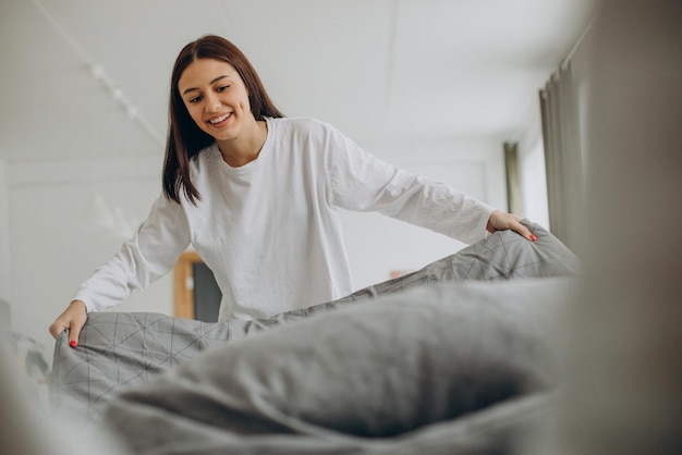 Foto gratuita mujer haciendo su cama después de dormir por la mañana