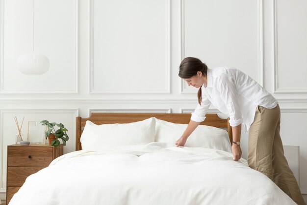 Mujer haciendo su cama, estilo interior escandinavo