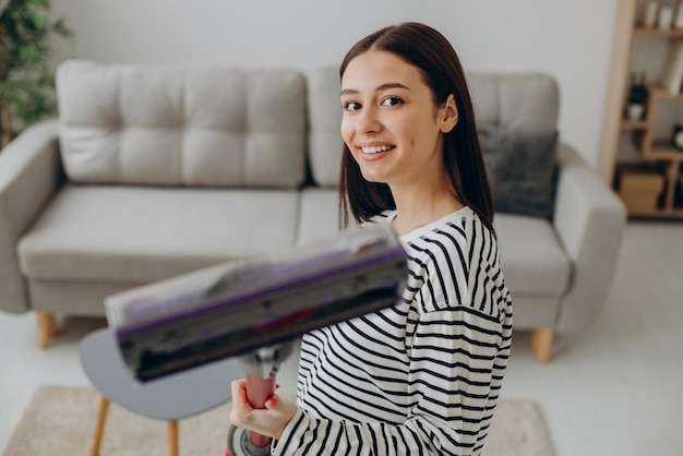 Foto gratuita mujer haciendo tareas domésticas con aspiradora recargable