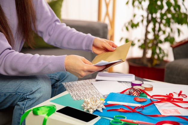 Mujer haciendo tarjetas de felicitación para Año Nuevo y Navidad 2021 para amigos o familiares, reserva de chatarra, bricolaje