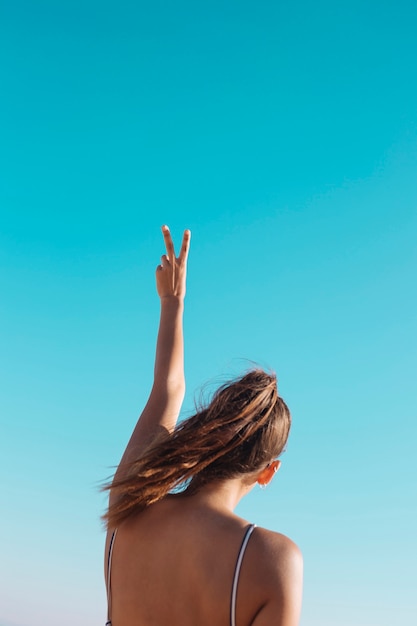 Mujer haciendo v suspiro en el cielo