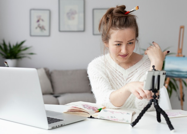 Mujer haciendo un vlog de arte en casa con su teléfono