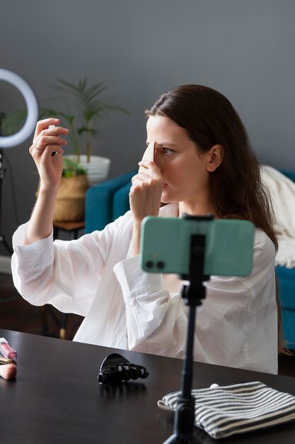 Mujer haciendo un vlog de maquillaje con su smartphone