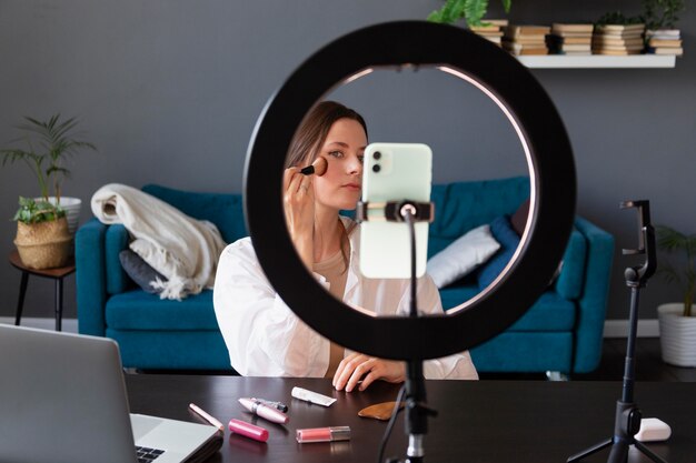 Mujer haciendo un vlog de maquillaje con su smartphone