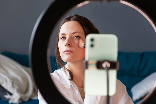 Mujer haciendo un vlog de maquillaje con su smartphone